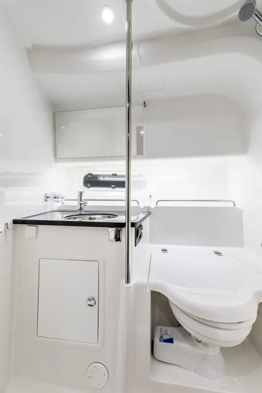 Modern white bathroom featuring a shower, toilet, sink, and storage cabinet. Sleek design with minimalistic fixtures.